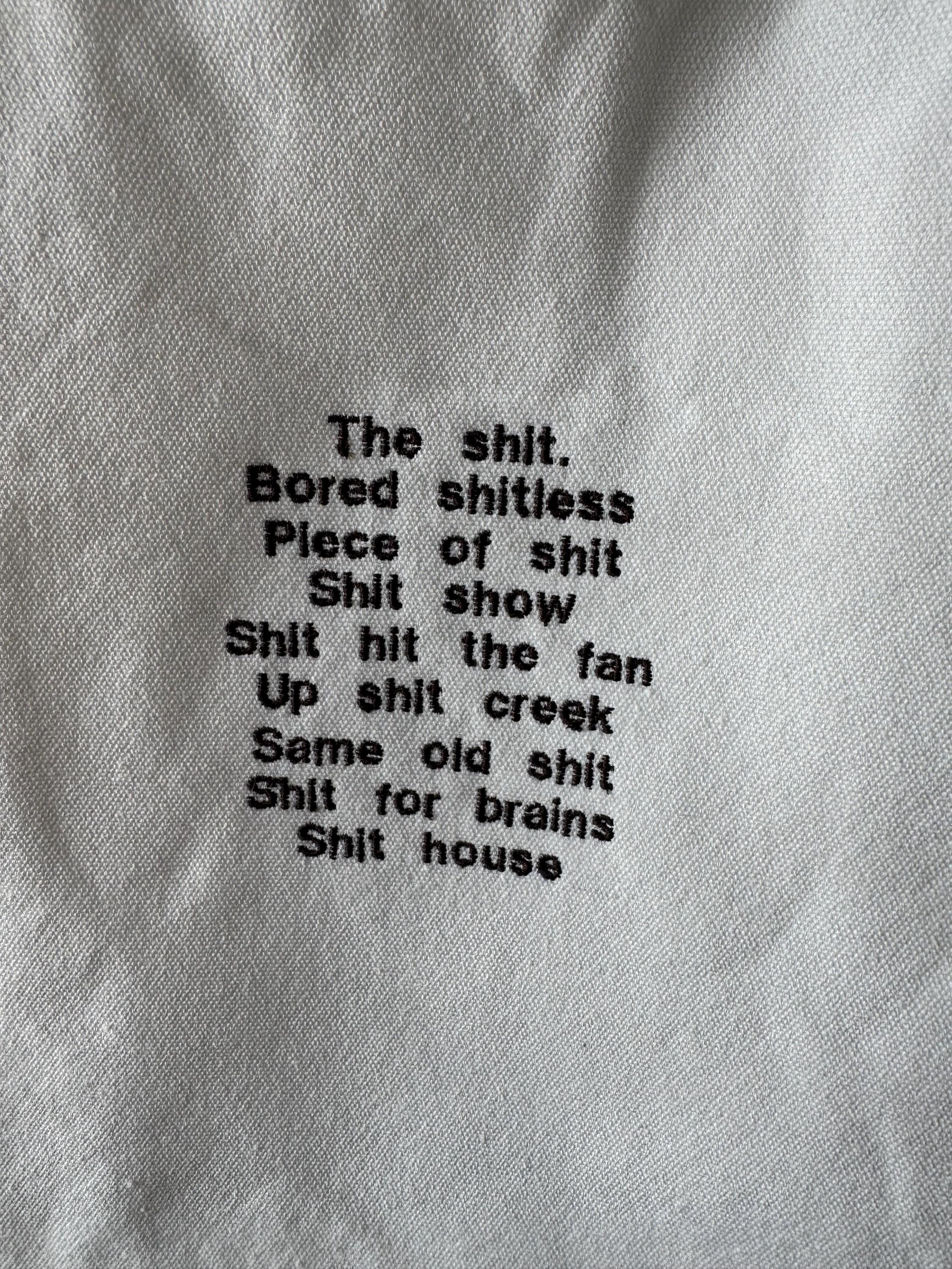 White tote bag with shit uk slang quotes embroidered in brown.