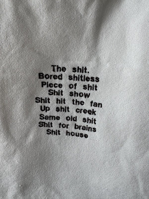 White tote bag with shit uk slang quotes embroidered in brown.
