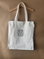 White tote bag with shit uk slang quotes embroidered in brown.
