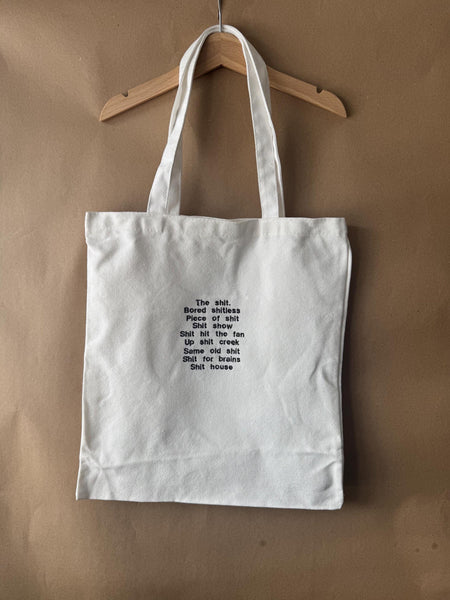 White tote bag with shit uk slang quotes embroidered in brown.