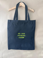 Black tote bag with ‘No one fucking cares’ embroidered in neon green