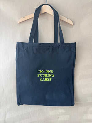 Black tote bag with ‘No one fucking cares’ embroidered in neon green