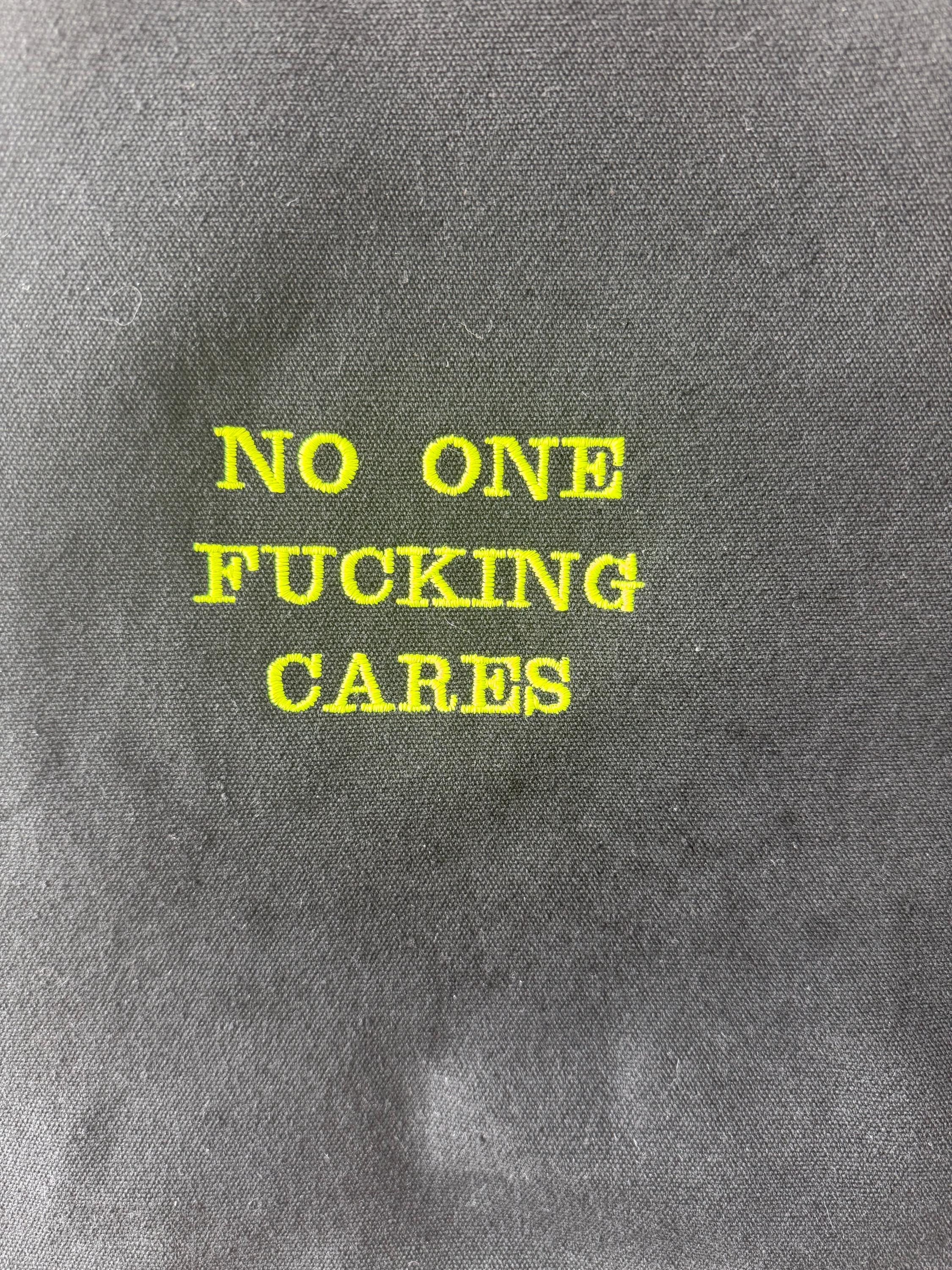 Black tote bag with ‘No one fucking cares’ embroidered in neon green
