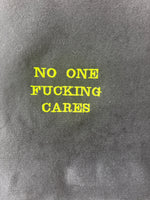 Black tote bag with ‘No one fucking cares’ embroidered in neon green