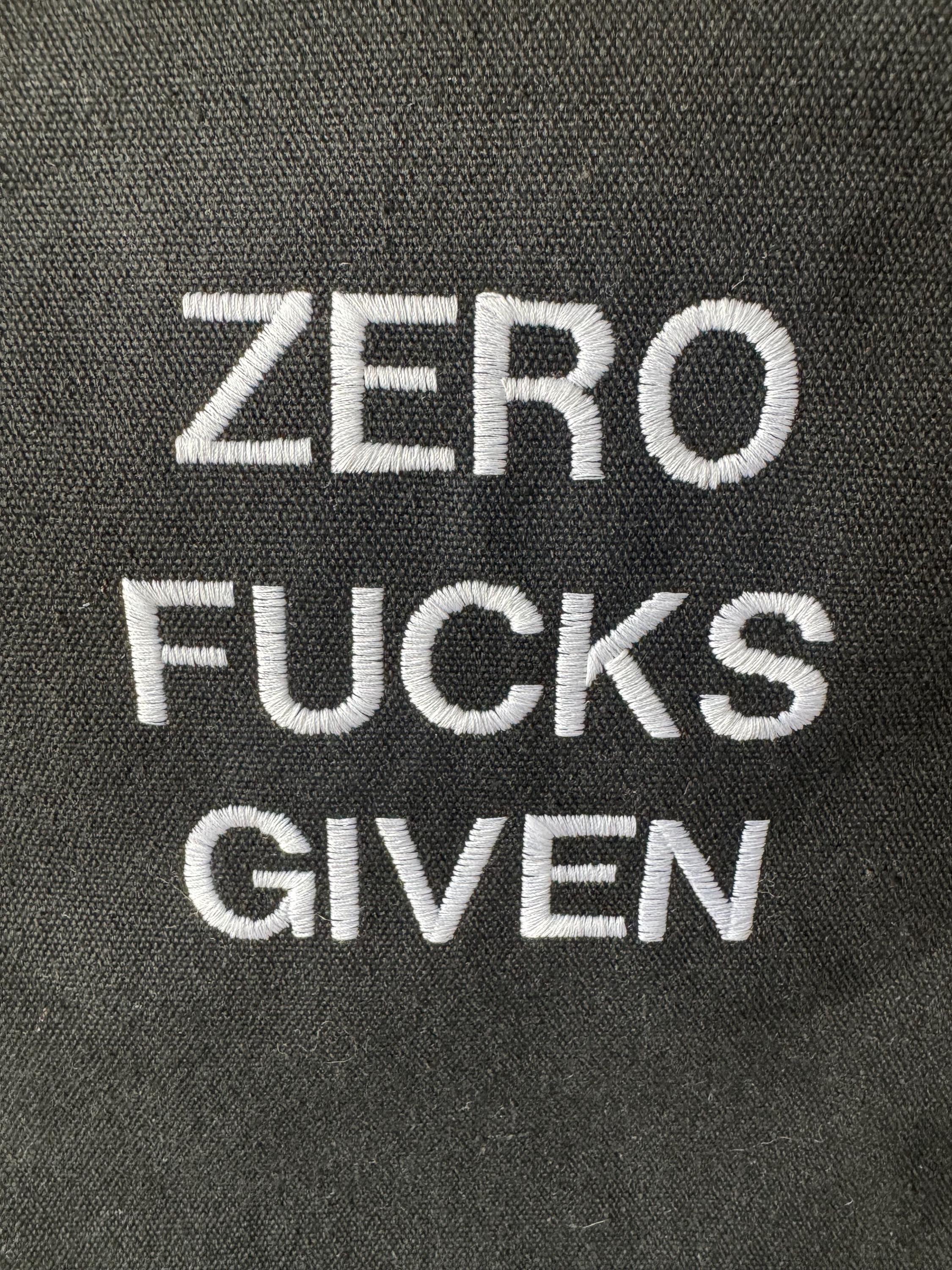 Black tote bag with ‘Zero fucks given’ embroidered in white.