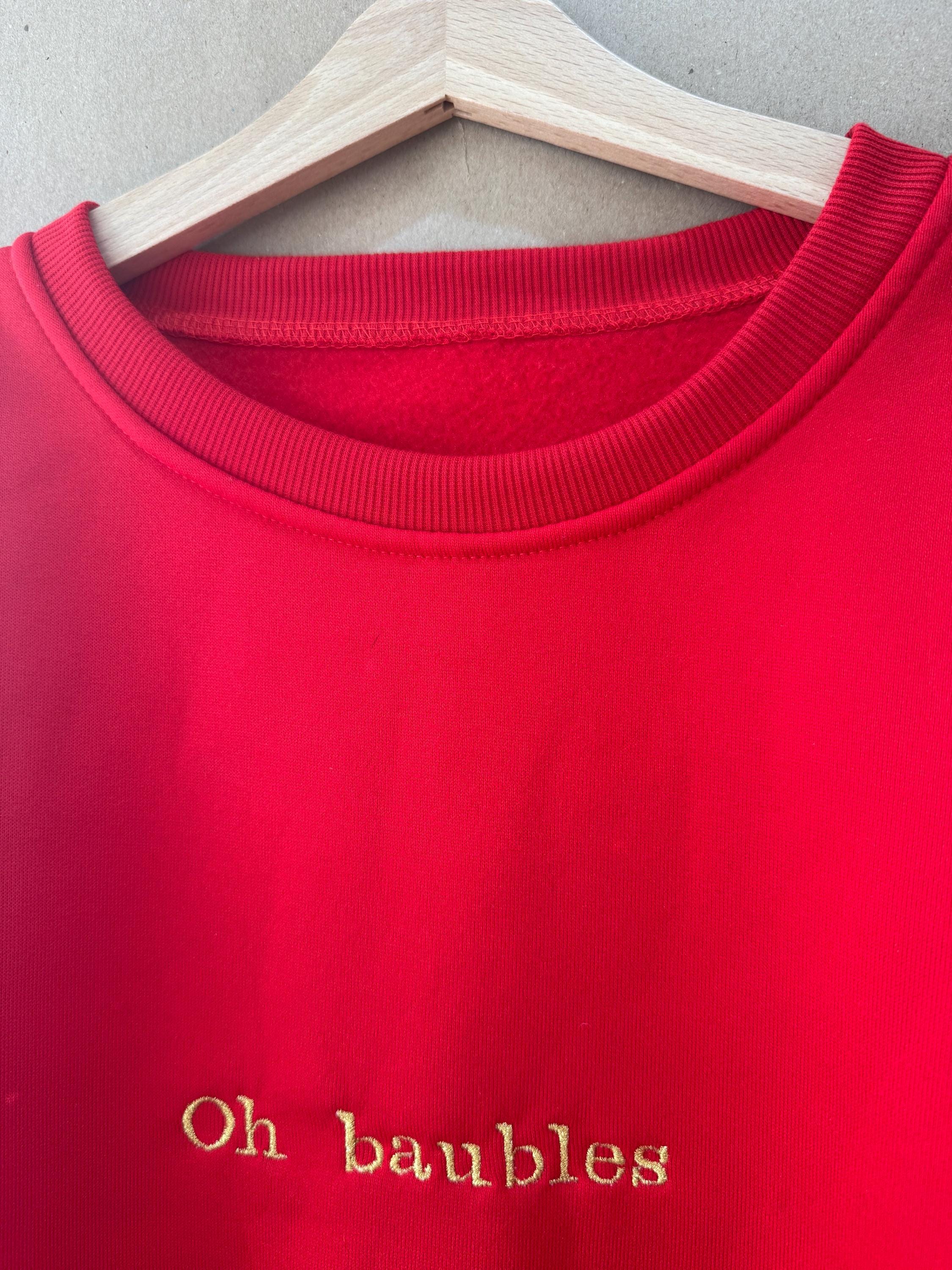 Christmas jumper in red, ‘Oh baubles’ embroidered in gold
