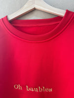 Christmas jumper in red, ‘Oh baubles’ embroidered in gold