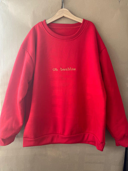Christmas jumper in red, ‘Oh baubles’ embroidered in gold