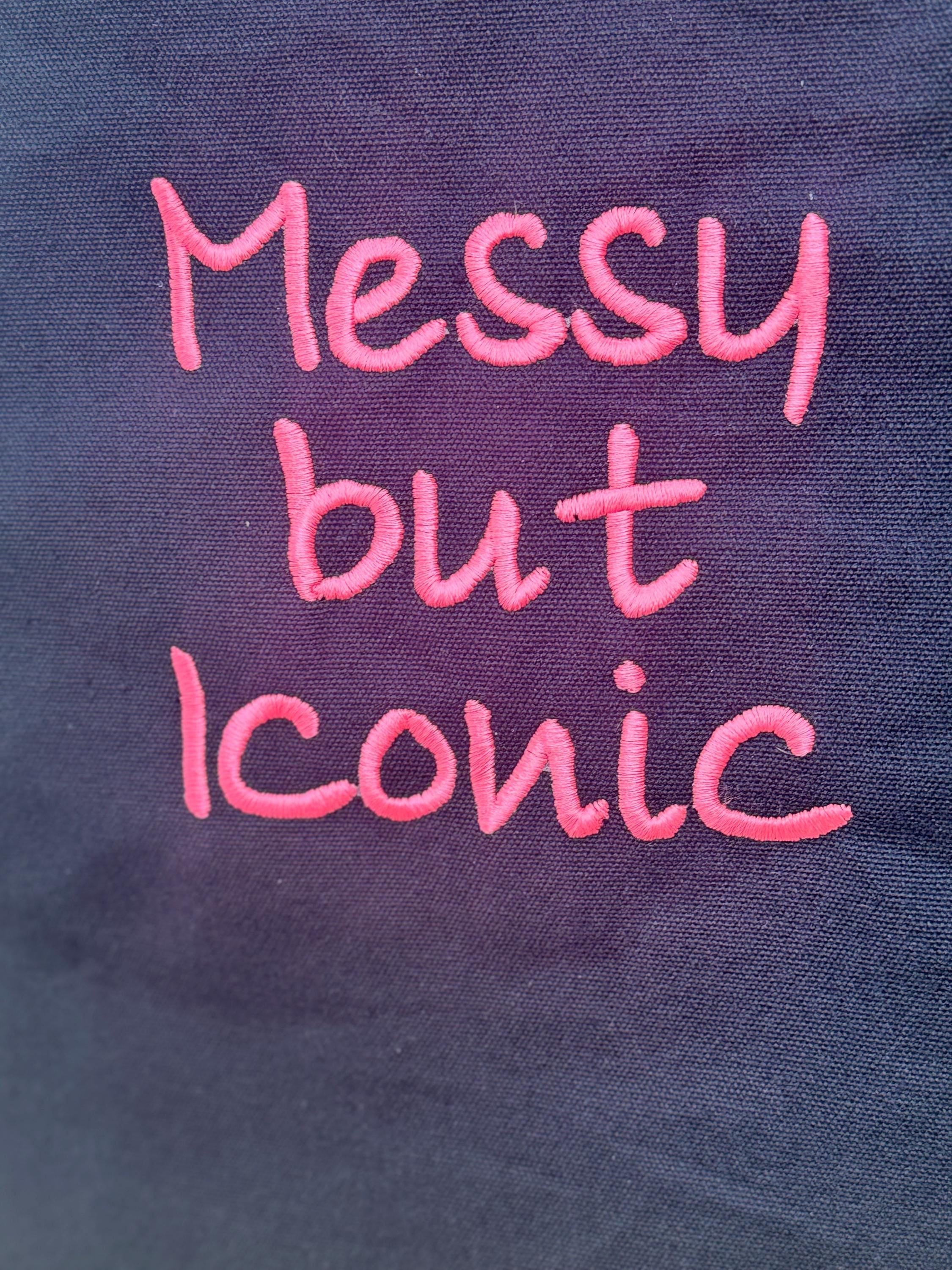 Black tote bag with ‘Messy but Iconic’ embroidered in neon pink