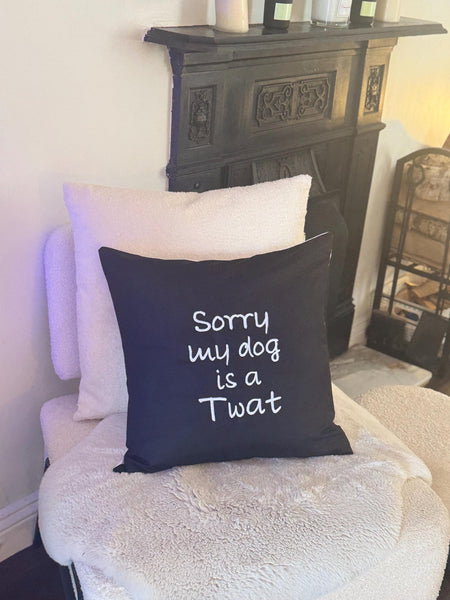 Black cushion cover with ‘Sorry my dog is a Twat’ embroidered in white.