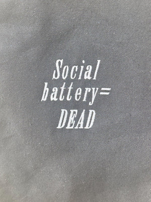 Black tote bag with ‘Social battery= DEAD’ embroidered in white.