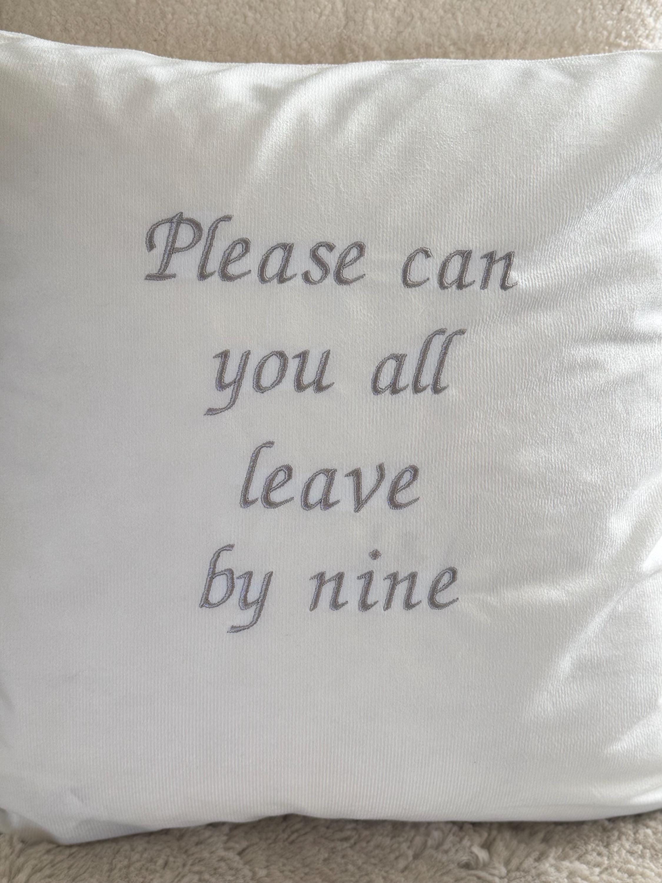White cushion cover with ‘please can you all leave by nine’ embroidered in silver