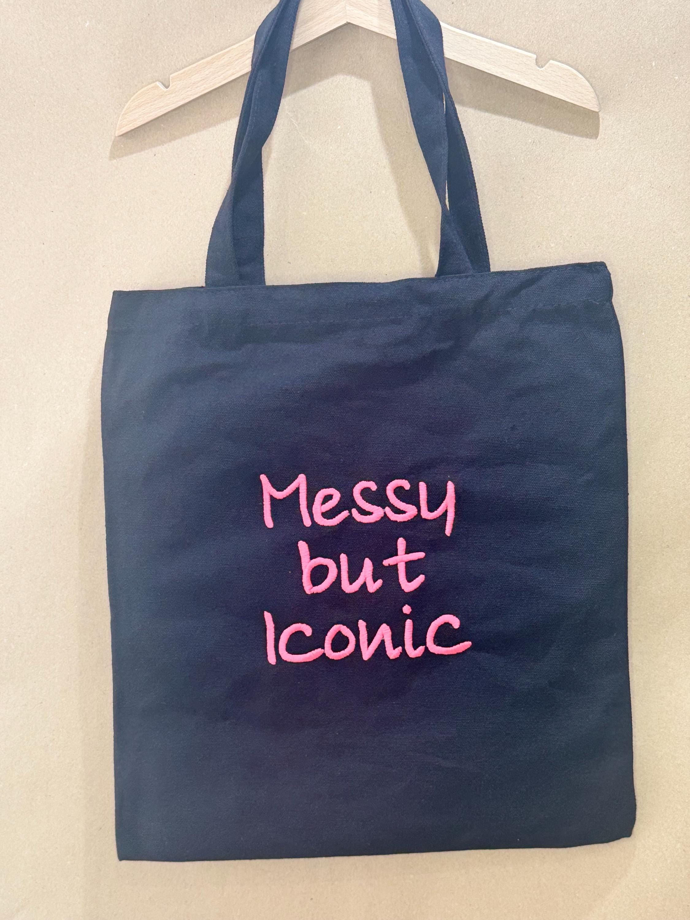 Black tote bag with ‘Messy but Iconic’ embroidered in neon pink