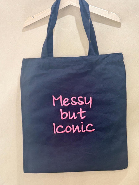 Black tote bag with ‘Messy but Iconic’ embroidered in neon pink