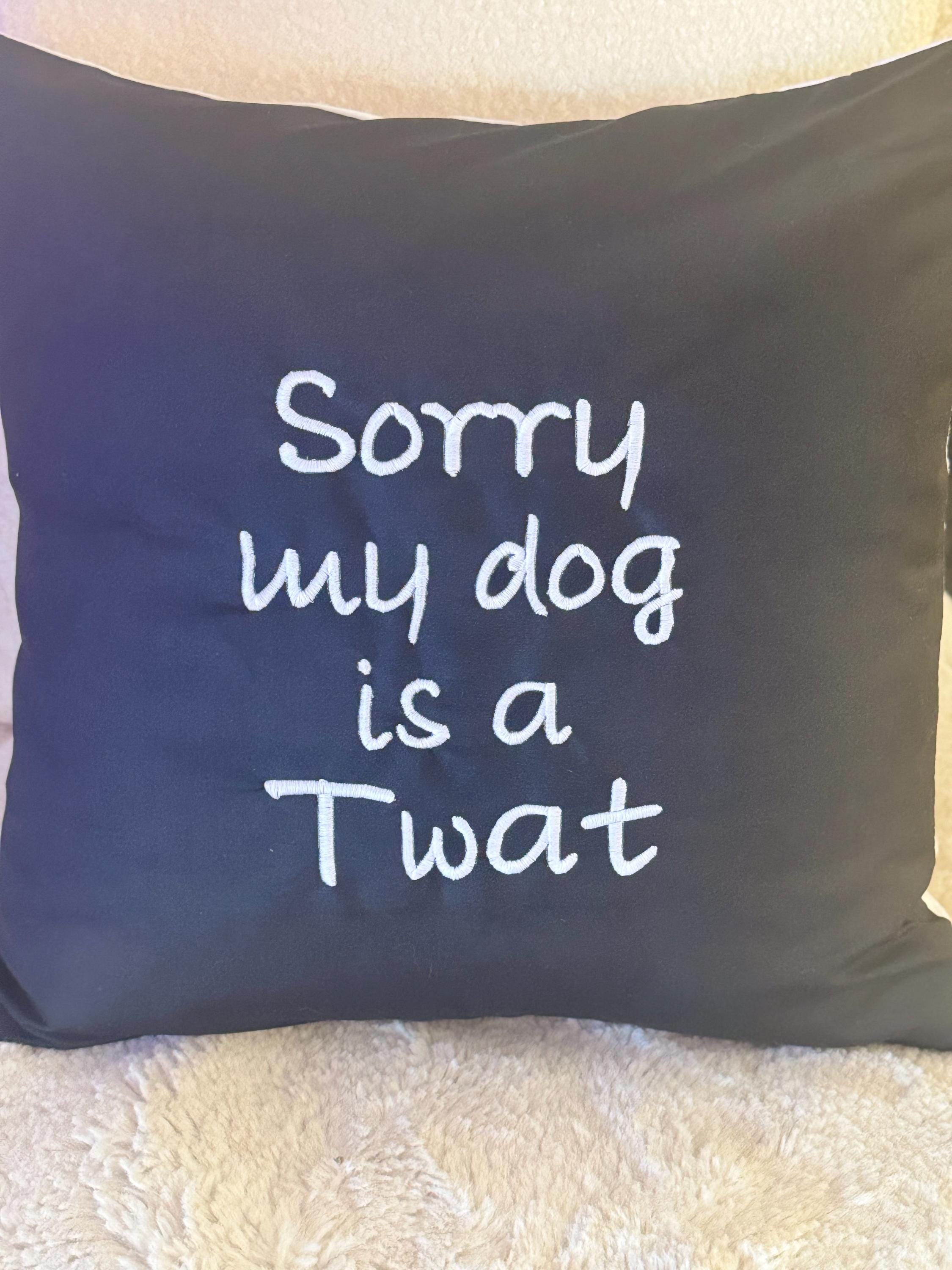 Black cushion cover with ‘Sorry my dog is a Twat’ embroidered in white.